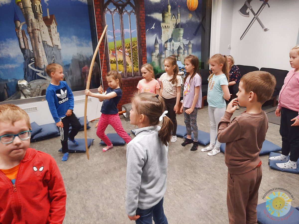 Dziewczynka w zabawnej pozie trzymająca łuk - Przedszkole Samorządowe Nr 2 Pod Słonkiem w Białymstoku