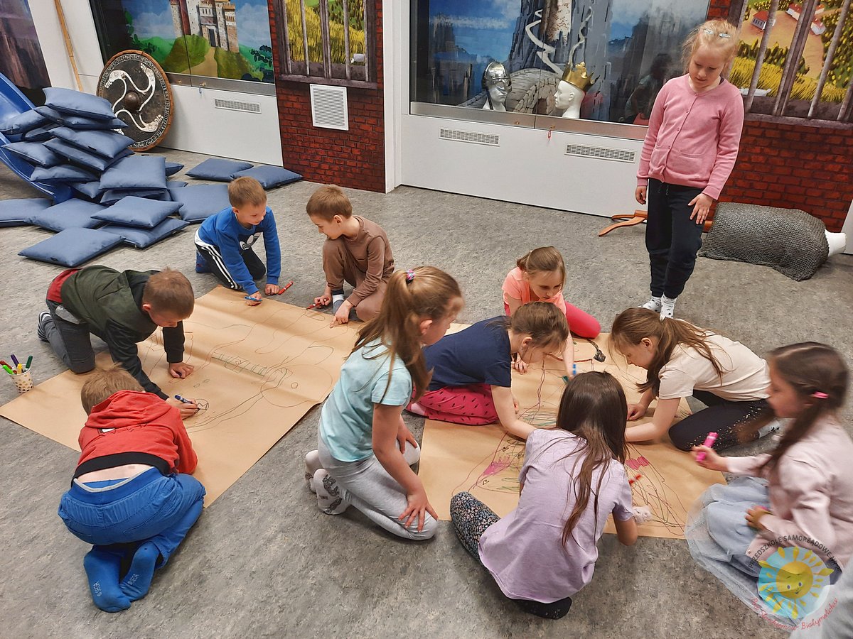 Grupka dzieci koloruje odrysowany kształt na kartce papieru  - Przedszkole Samorządowe Nr 2 Pod Słonkiem w Białymstoku