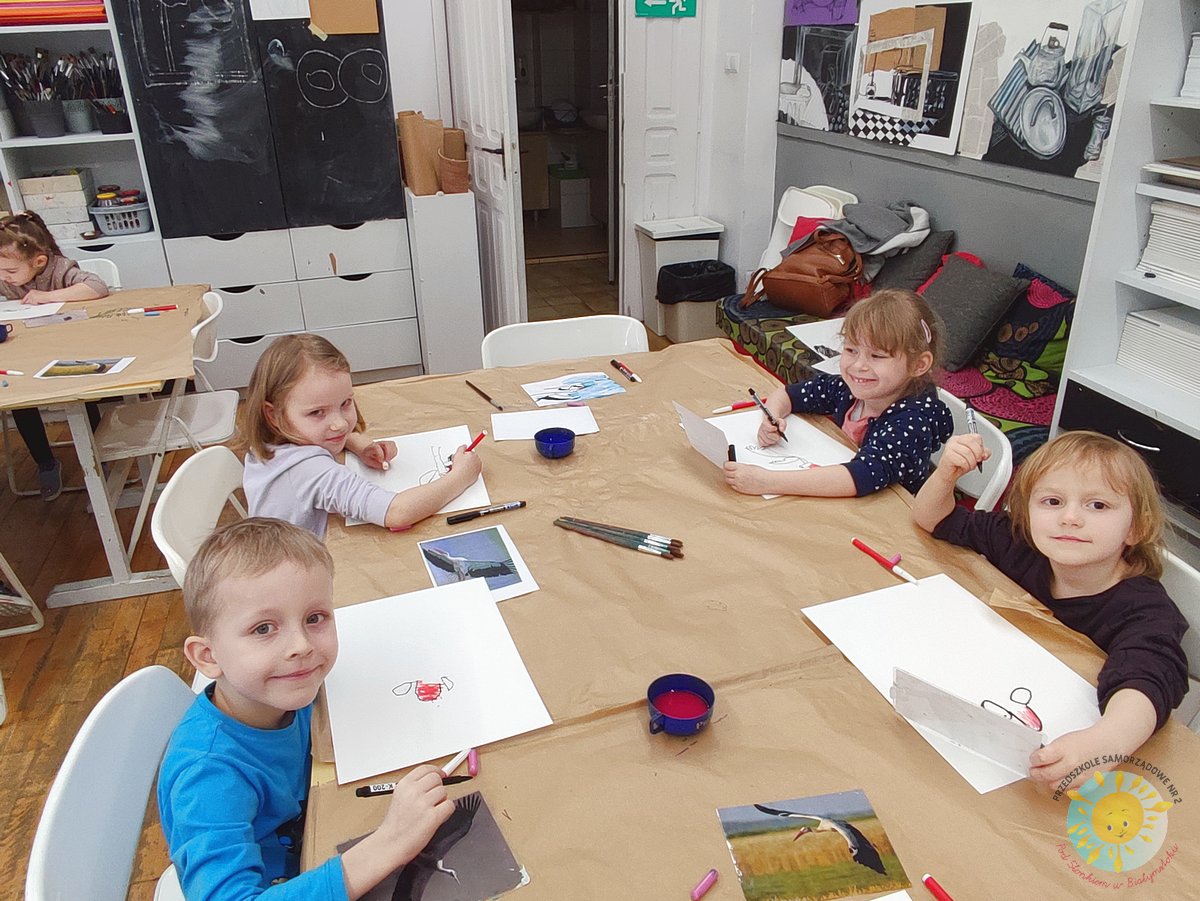 Uśmiechnięte dzieci siedzą przy stole i malują na kartkach papieru - Przedszkole Samorządowe Nr 2 Pod Słonkiem