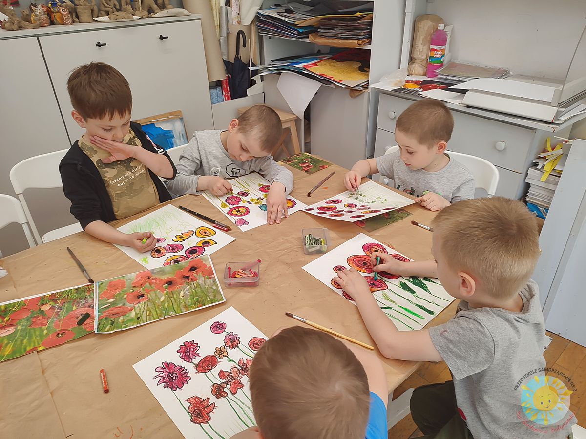 Kilkoro dzieci z przedszkola siedzi przy stole i rysuje maki - Przedszkole Samorządowe Nr 2 Pod Słonkiem w Białymstoku
