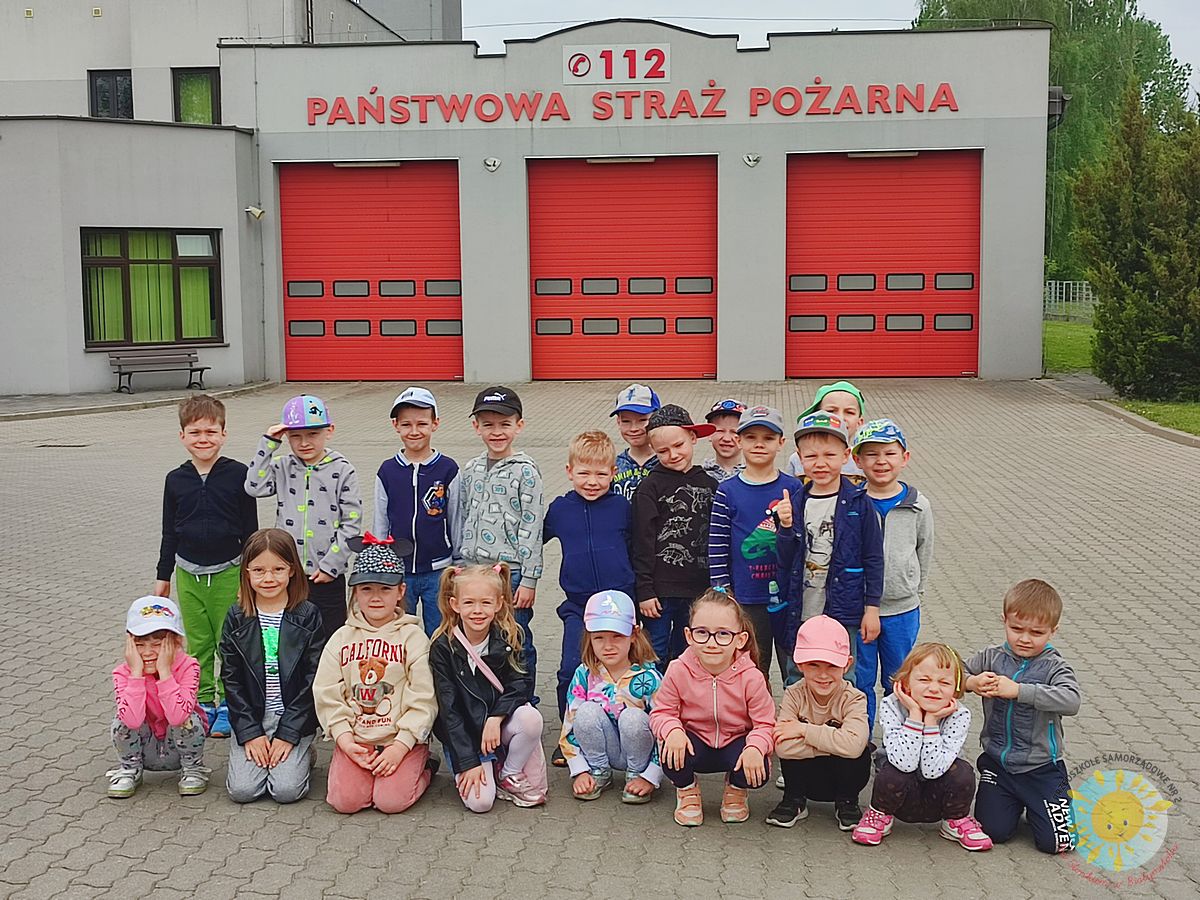 Grupka dzieci na tle wjazdu do Państwowej Straży Pożarnej - Przedszkole Samorządowe Nr 2 Pod Słonkiem w Białymstoku