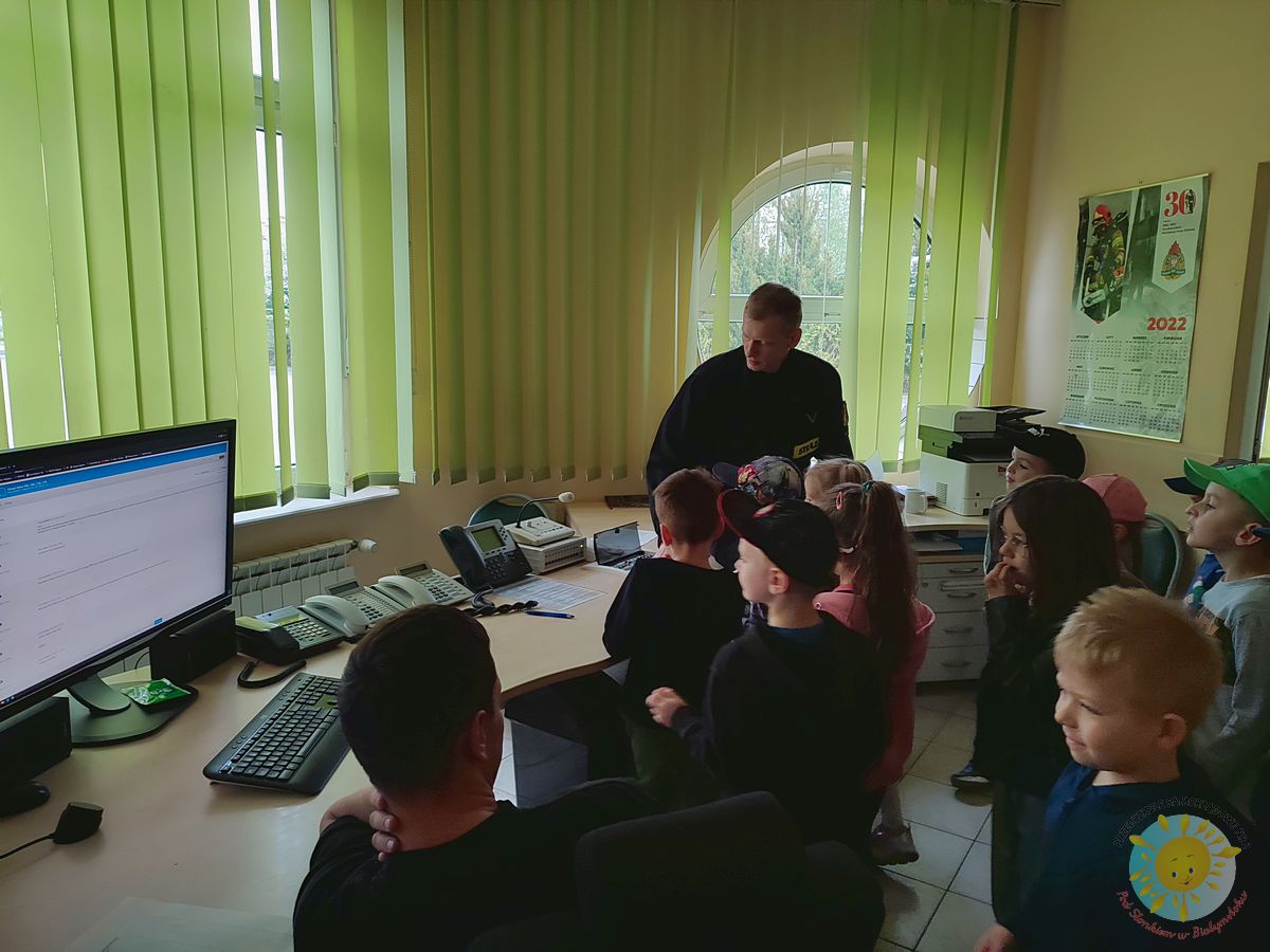 Kilkoro dzieci obserwujących pracę w dyspozytorni strażaków  - Przedszkole Samorządowe Nr 2 Pod Słonkiem w Białymstoku