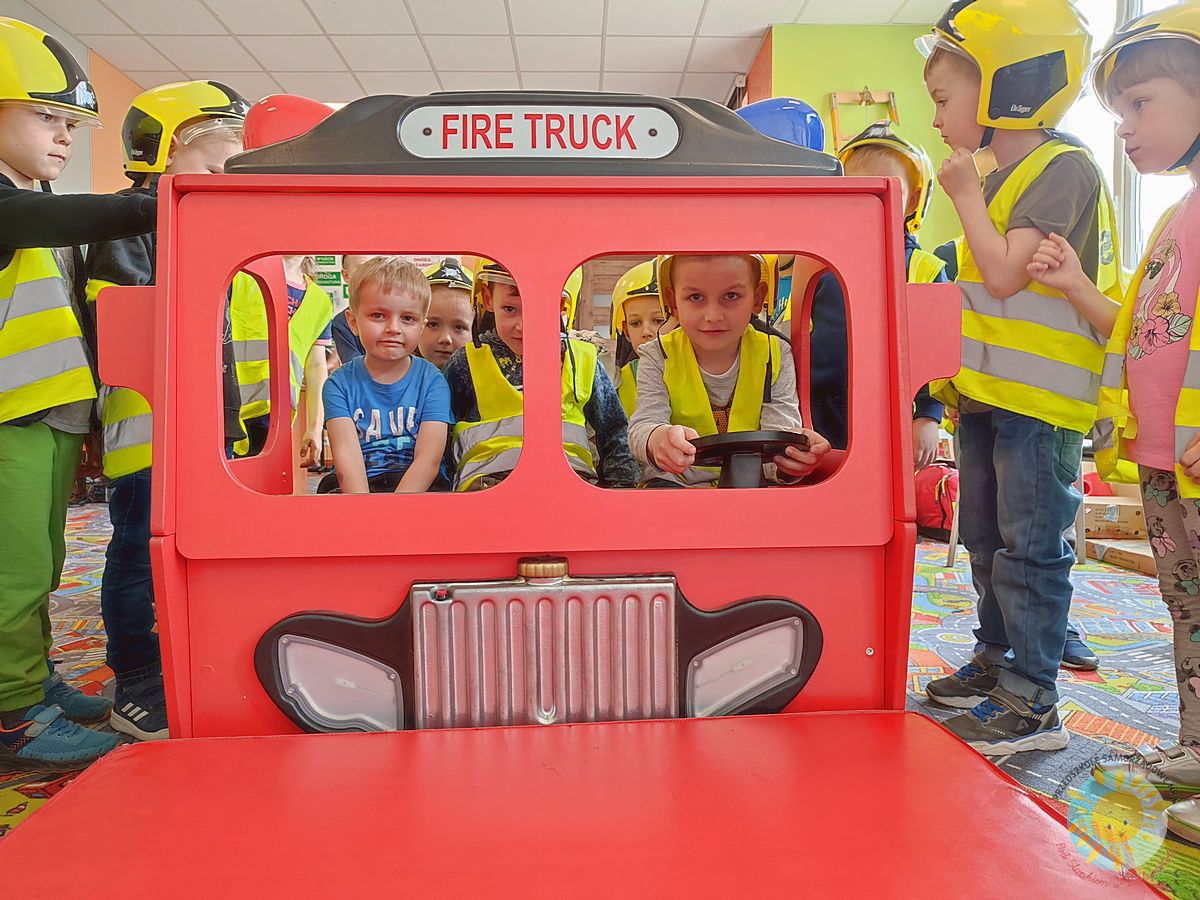 Grupka dzieci siedząca w zabawkowym samochodzie strażackim  - Przedszkole Samorządowe Nr 2 Pod Słonkiem w Białymstoku