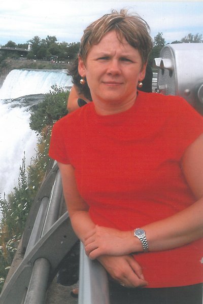 Kobieta w czerwonej koszulce, stojąca nad wodospadem, oparta o poręcz  - Przedszkole Samorządowe Nr 2 Pod Słonkiem w Białymstoku