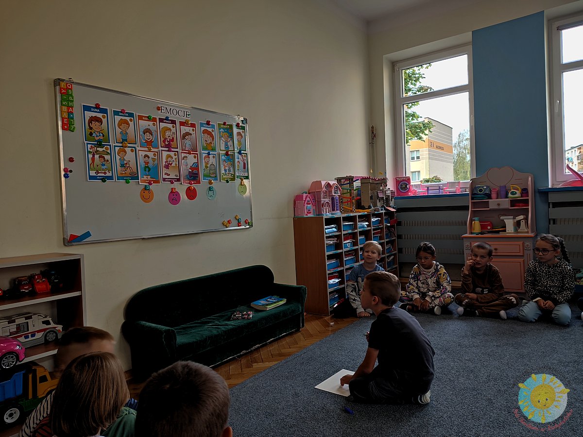 Dziecko siedzi na dywanie i zapisuje coś na kartce - Przedszkole Samorządowe Nr 2 Pod Słonkiem w Białymstoku