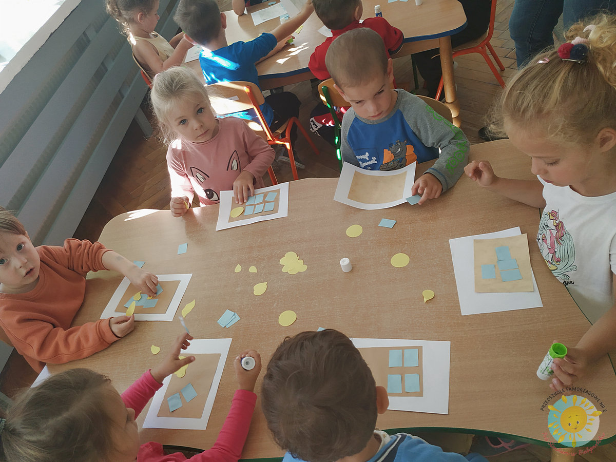 Dzieci siedzą przy stole i wyklejają na kartkach - Przedszkole Samorządowe Nr 2 Pod Słonkiem w Białymstoku
