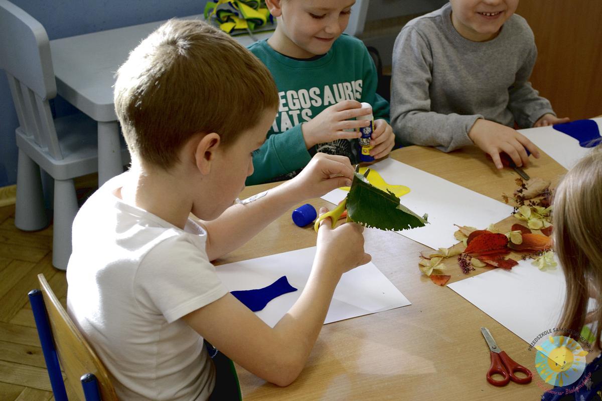 Dzieci siedzą przy stole, malując jesienne liście - Przedszkole Samorządowe Nr 2 Pod Słonkiem w Białymstoku