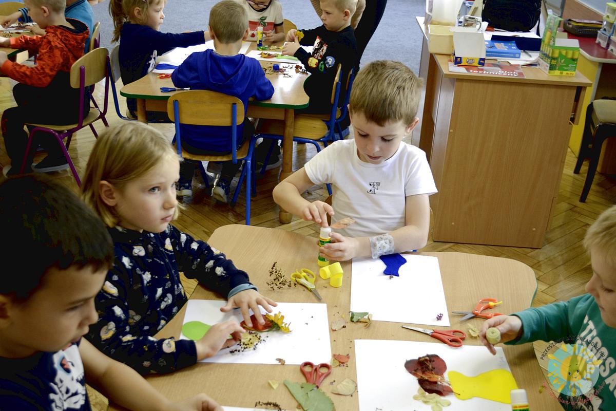Dzieci siedzą przy stole, malując jesienne liście - Przedszkole Samorządowe Nr 2 Pod Słonkiem w Białymstoku