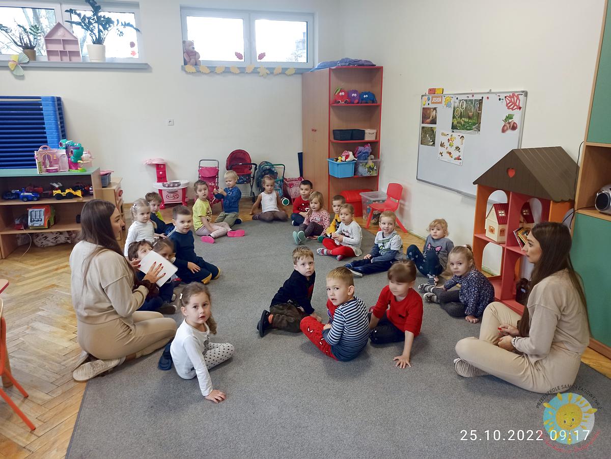 Dzieci siedzą na dywanie razem z panią, która im tłumaczy różne rzeczy - Przedszkole Samorządowe Nr 2 Pod Słonkiem w Białymstoku