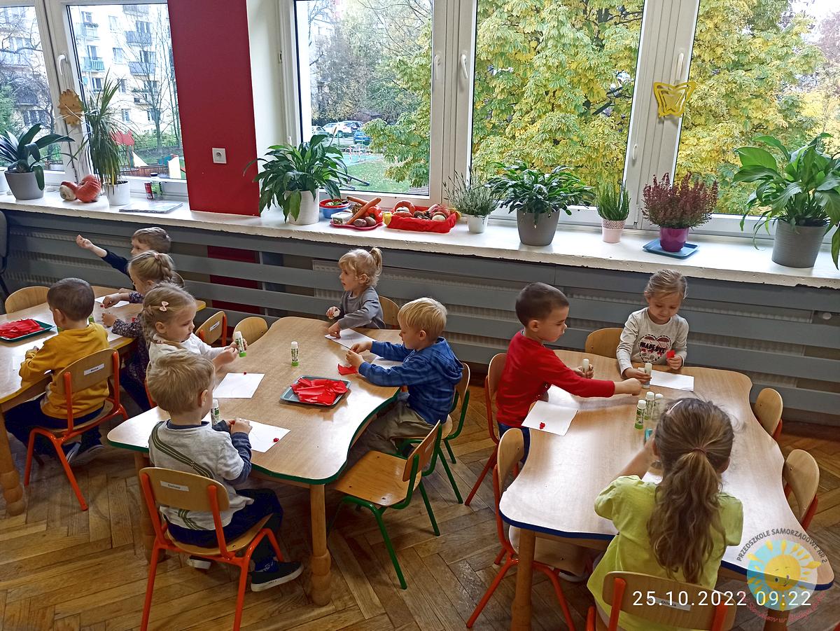 Dzieci pracują przy stole, tworząc jesienny obrazek wiewiórki z liści - Przedszkole Samorządowe Nr 2 Pod Słonkiem w Białymstoku