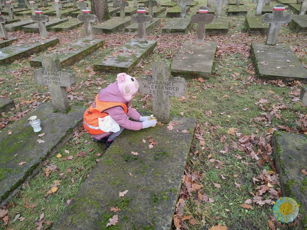 Dzieci stawiają znicze na grobach cmentarza wojskowego - Przedszkole Samorządowe Nr 2 Pod Słonkiem w Białymstoku