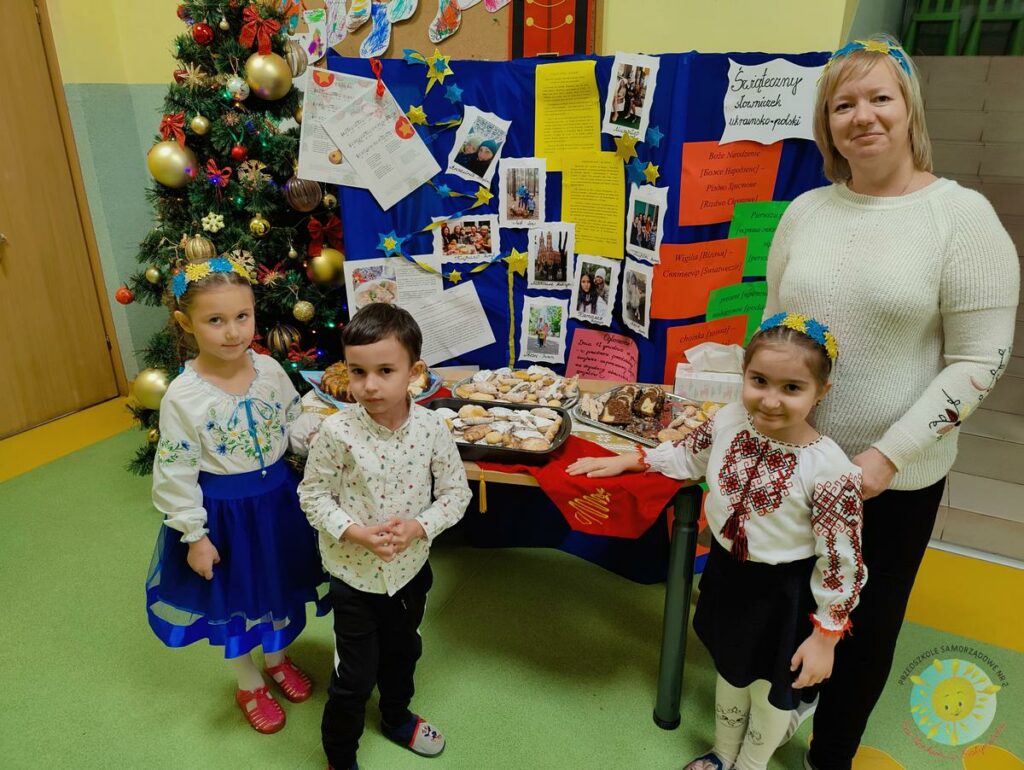 Dzieci i Pani z Ukrainy  stoi przy stoliku ukraińskich wypieków - Przedszkole Samorządowe Nr 2 Pod Słonkiem w Białymstoku