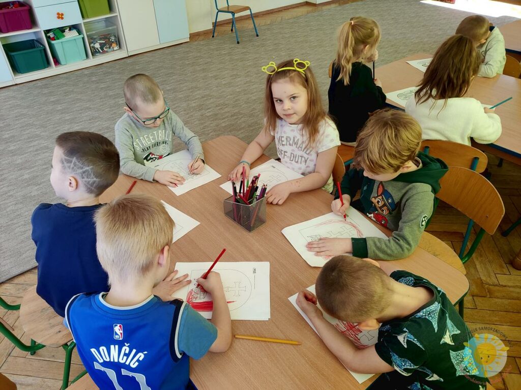 Dzieci z przedszkola siedzą przy stoliku i kolorują  herb warszawy - Przedszkole Samorządowe Nr 2 Pod Słonkiem w Białymstoku