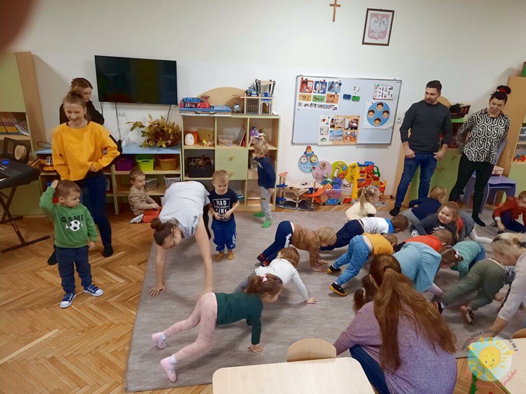 Dzieci bawią się na dywanie przy dźwiękach grających przez panią z rytmiki - Przedszkole Samorządowe Nr 2 Pod Słonkiem w Białymstoku