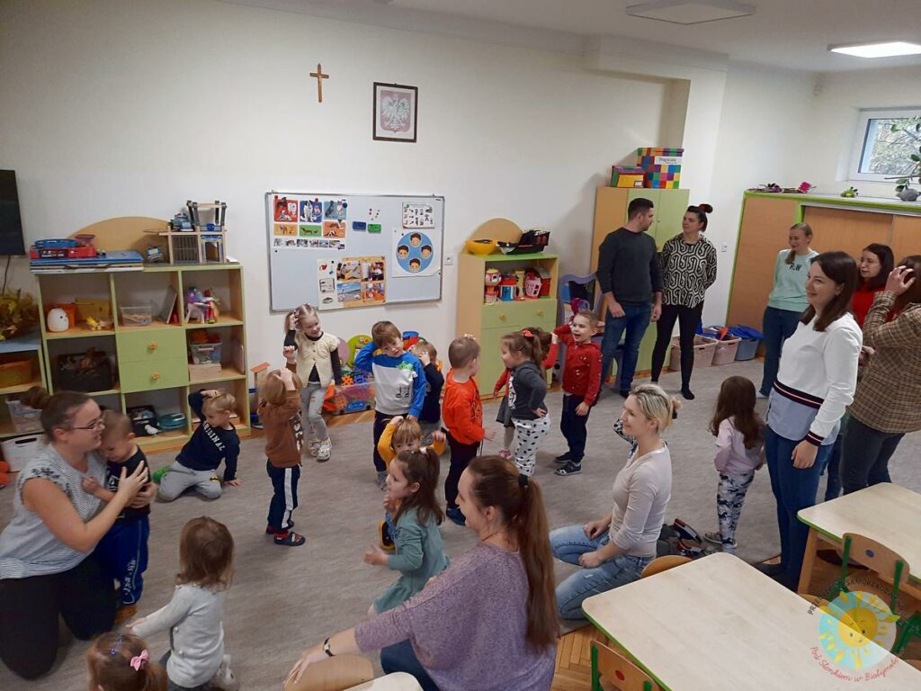 Dzieci bawią się na dywanie przy dźwiękach grających przez panią z rytmiki - Przedszkole Samorządowe Nr 2 Pod Słonkiem w Białymstoku
