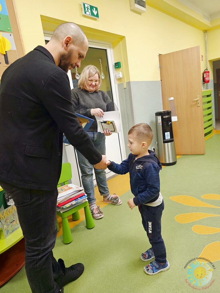 Dziecko wieku przedszkolnym odbiera nagrodę w postaci książki od dyrektora przedszkola - Przedszkole Samorządowe Nr 2 Pod Słonkiem w Białymstoku