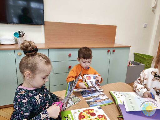 Siedzące dzieci przy stole i wykonują pracę plastyczną - Przedszkole Samorządowe Nr 2 Pod Słonkiem w Białymstoku