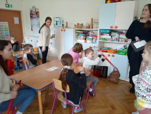 Siedzące studentki i dzieci przy stole - Przedszkole Samorządowe Nr 2 Pod Słonkiem w Białymstoku