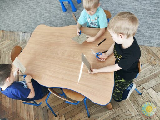 Siedzące dzieci przy stole i wykonują pracę plastyczną - Przedszkole Samorządowe Nr 2 Pod Słonkiem w Białymstoku

