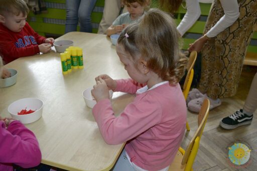 Siedzące dzieci przy stole i wykonują pracę plastyczną - Przedszkole Samorządowe Nr 2 Pod Słonkiem w Białymstoku