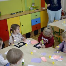 Siedzące dzieci przy stole i wykonują pracę plastyczną - Przedszkole Samorządowe Nr 2 Pod Słonkiem w Białymstoku
