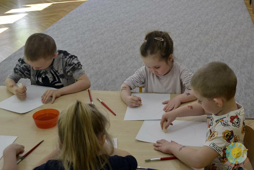 Siedzące dzieci przy przedszkolnym stoliku, wykonują pracę - Przedszkole Samorządowe Nr 2 Pod Słonkiem w Białymstoku