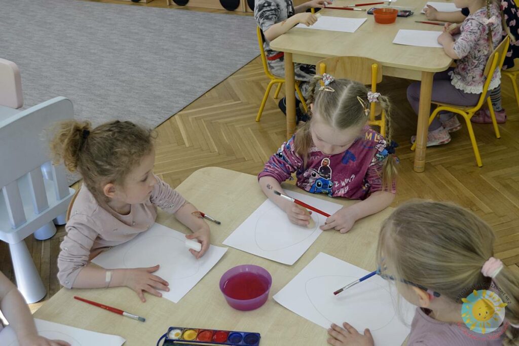 Siedzące dzieci przy przedszkolnym stoliku, wykonują pracę - Przedszkole Samorządowe Nr 2 Pod Słonkiem w Białymstoku