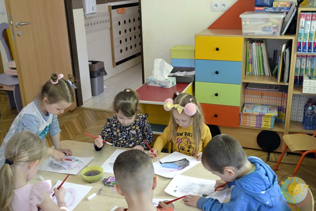 Siedzące dzieci przy przedszkolnym stoliku, wykonują pracę - Przedszkole Samorządowe Nr 2 Pod Słonkiem w Białymstoku