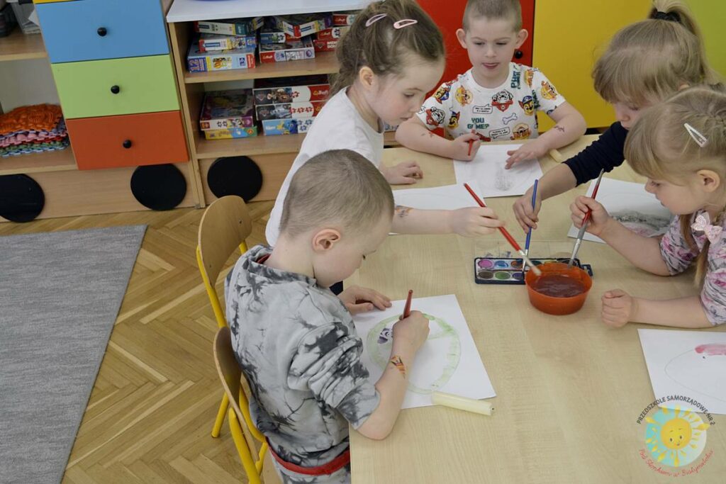 Siedzące dzieci przy przedszkolnym stoliku, wykonują pracę - Przedszkole Samorządowe Nr 2 Pod Słonkiem w Białymstoku