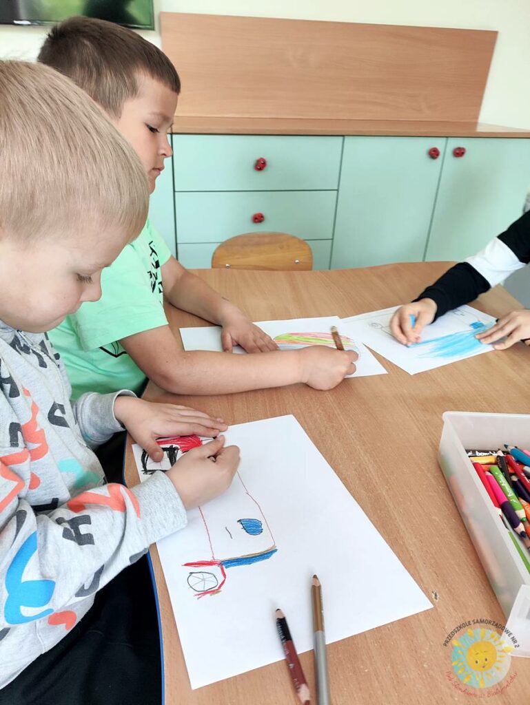 Siedzące dzieci przy przedszkolnym stoliku, wykonują pracę - Przedszkole Samorządowe Nr 2 Pod Słonkiem w Białymstoku