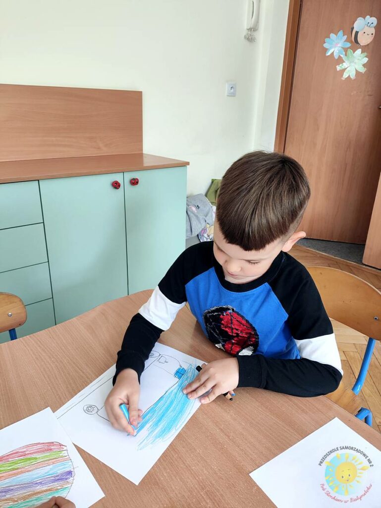 Siedzące dzieci przy przedszkolnym stoliku, wykonują pracę - Przedszkole Samorządowe Nr 2 Pod Słonkiem w Białymstoku