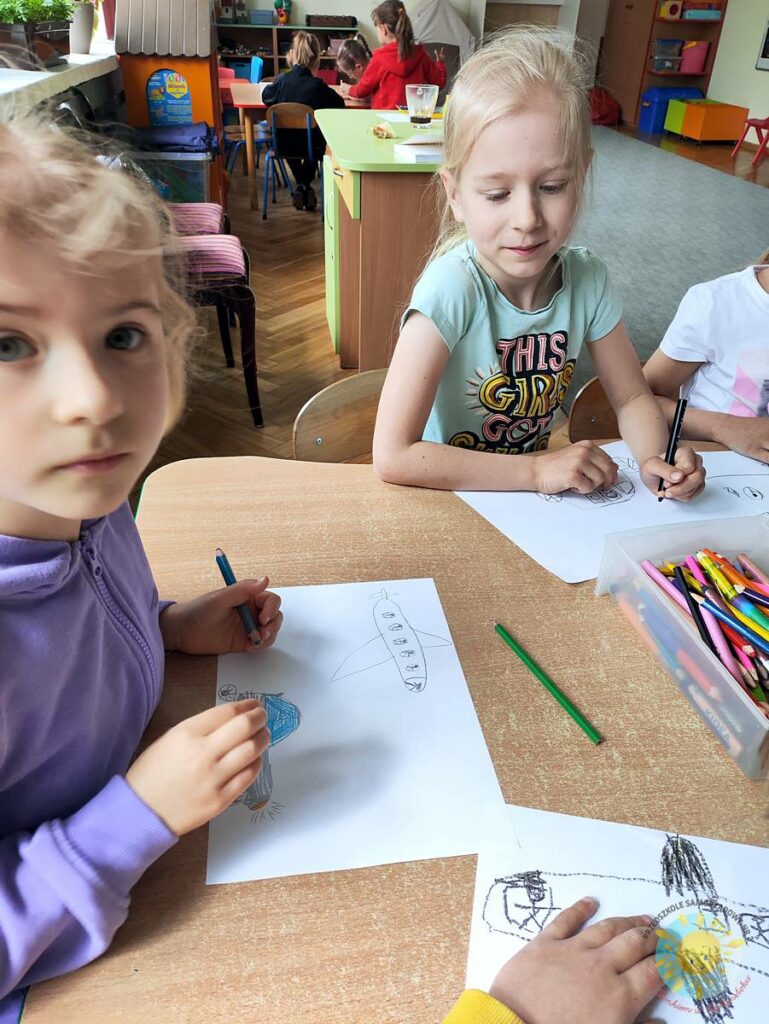Siedzące dzieci przy przedszkolnym stoliku, wykonują pracę - Przedszkole Samorządowe Nr 2 Pod Słonkiem w Białymstoku
