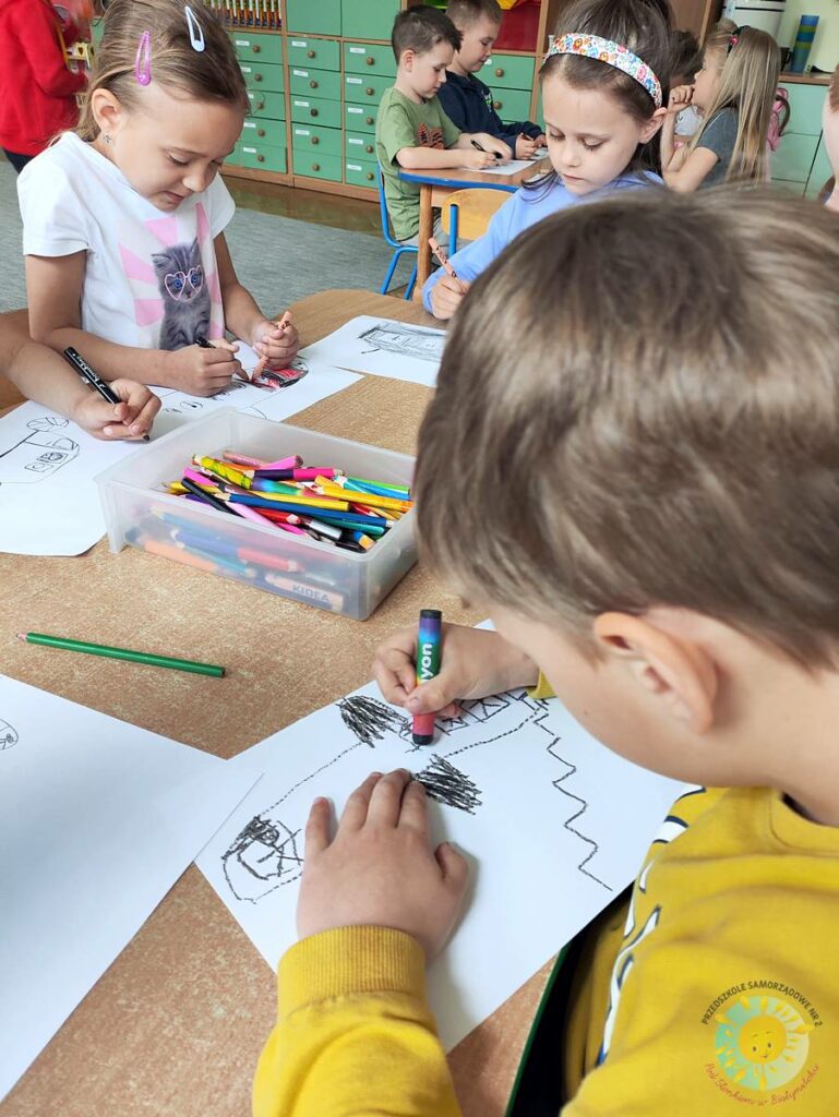 Siedzące dzieci przy przedszkolnym stoliku, wykonują pracę - Przedszkole Samorządowe Nr 2 Pod Słonkiem w Białymstoku