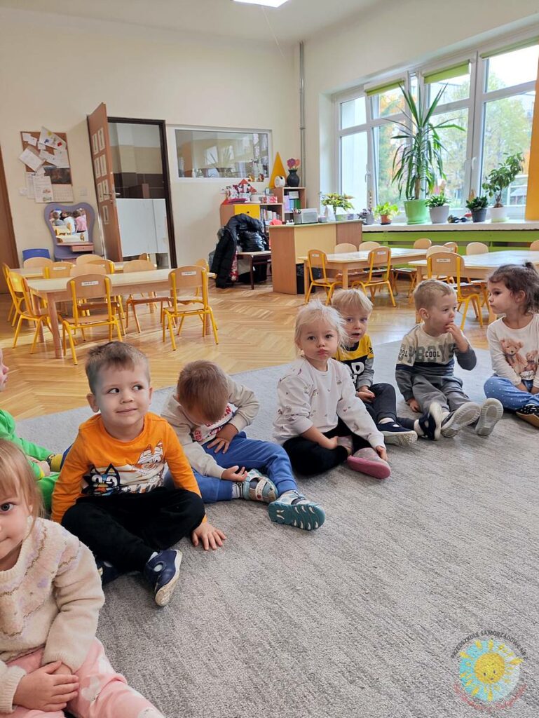 Siedzące dzieci na dywanie, które biorą udział w zajęciach - Przedszkole Samorządowe Nr 2 Pod Słonkiem w Białymstoku