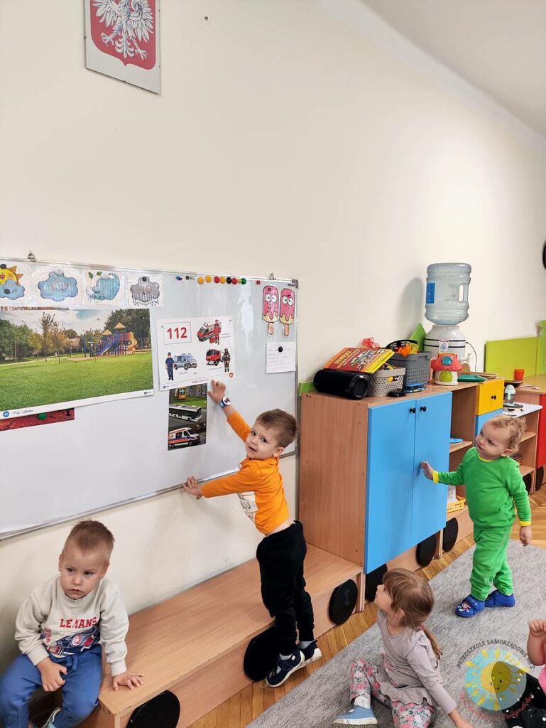 Stojące dziecko przy tablicy, wieszające obrazek - Przedszkole Samorządowe Nr 2 Pod Słonkiem w Białymstoku