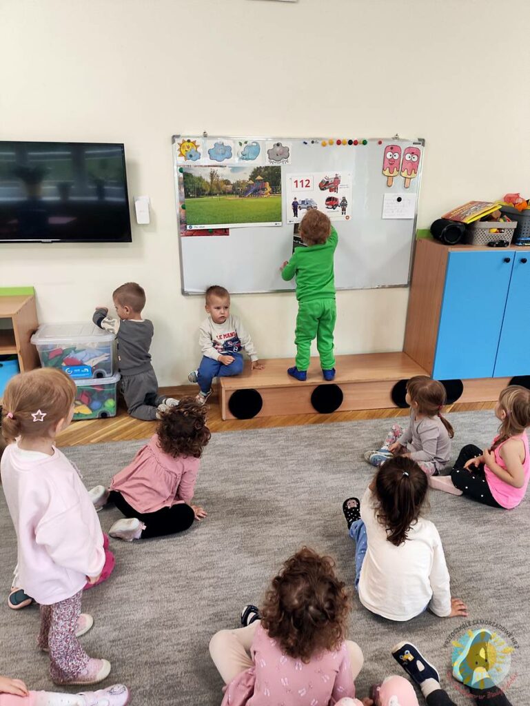 Stojące dziecko przy tablicy, wieszające obrazek - Przedszkole Samorządowe Nr 2 Pod Słonkiem w Białymstoku