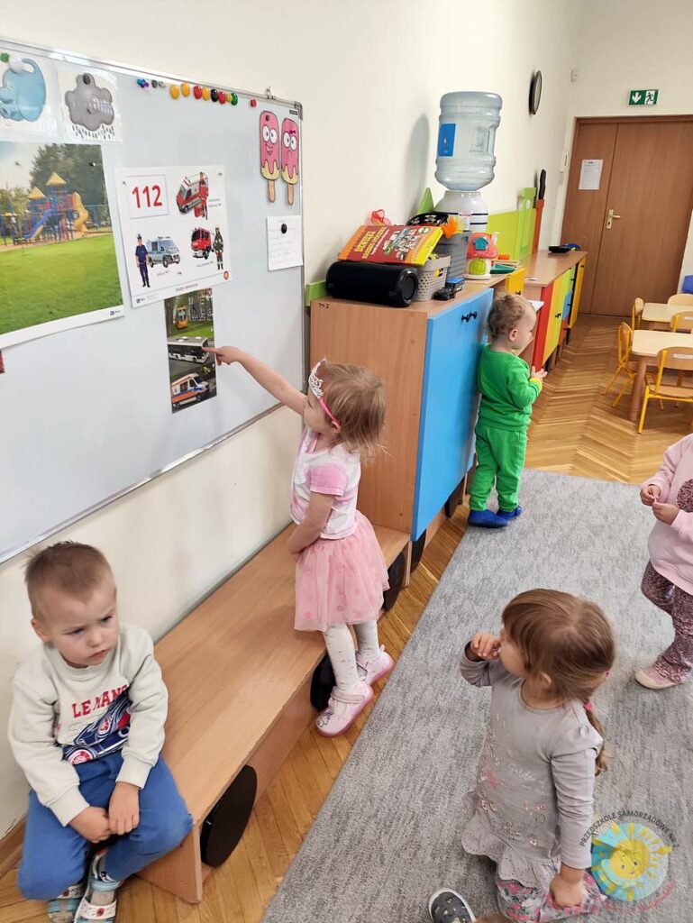 Stojące dziecko przy tablicy, wieszające obrazek - Przedszkole Samorządowe Nr 2 Pod Słonkiem w Białymstoku