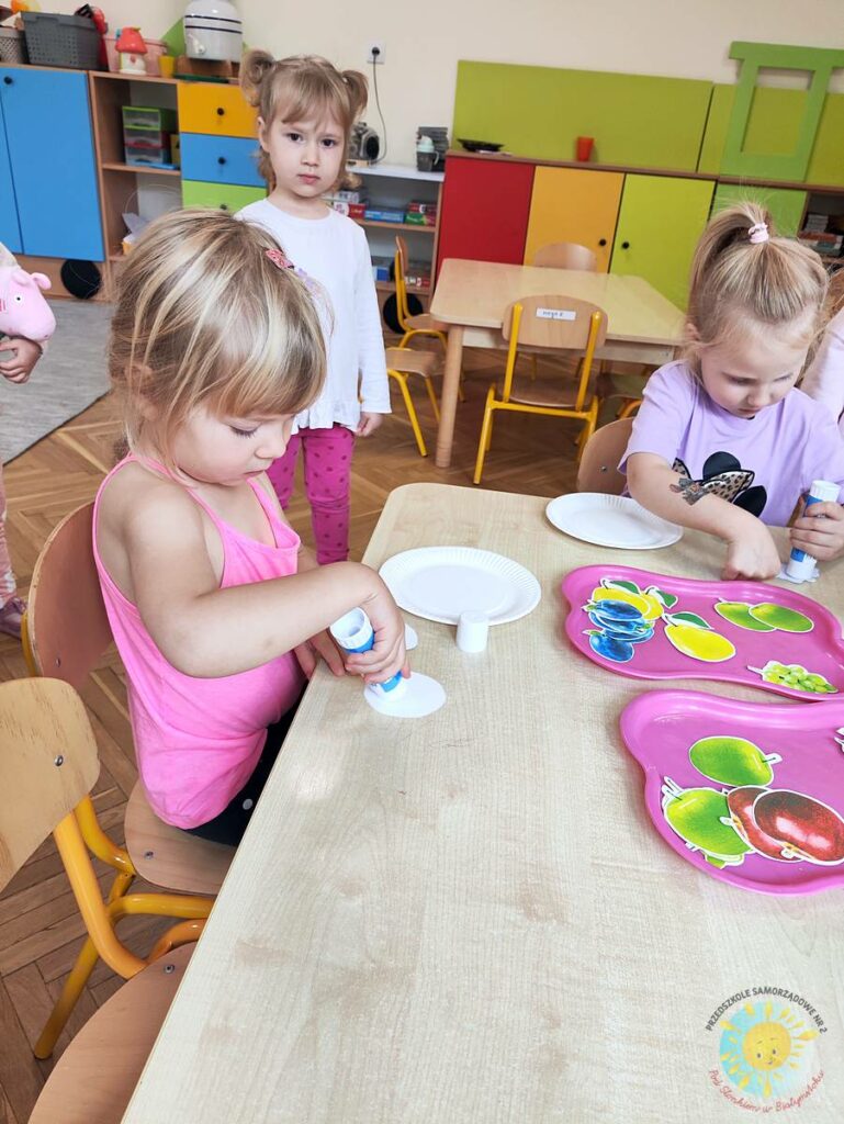 Siedzące dzieci przy stole i wykonują pracę plastyczną - Przedszkole Samorządowe Nr 2 Pod Słonkiem w Białymstoku