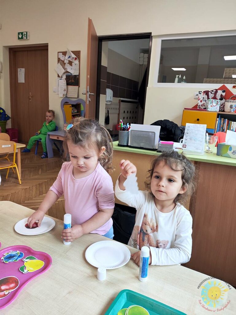 Siedzące dzieci przy stole i wykonują pracę plastyczną - Przedszkole Samorządowe Nr 2 Pod Słonkiem w Białymstoku