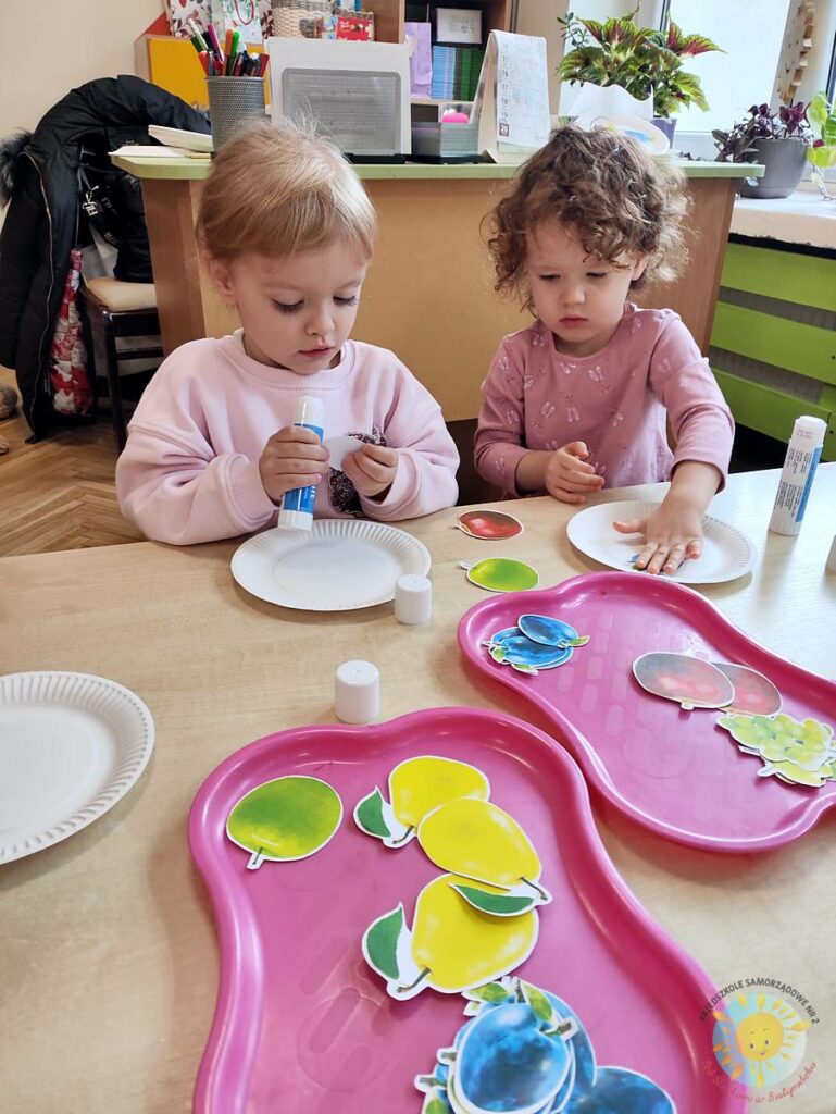 Siedzące dzieci przy stole i wykonują pracę plastyczną - Przedszkole Samorządowe Nr 2 Pod Słonkiem w Białymstoku