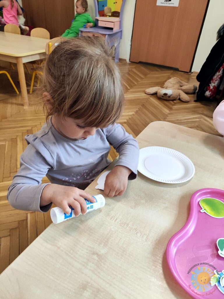 Siedzące dzieci przy stole i wykonują pracę plastyczną - Przedszkole Samorządowe Nr 2 Pod Słonkiem w Białymstoku