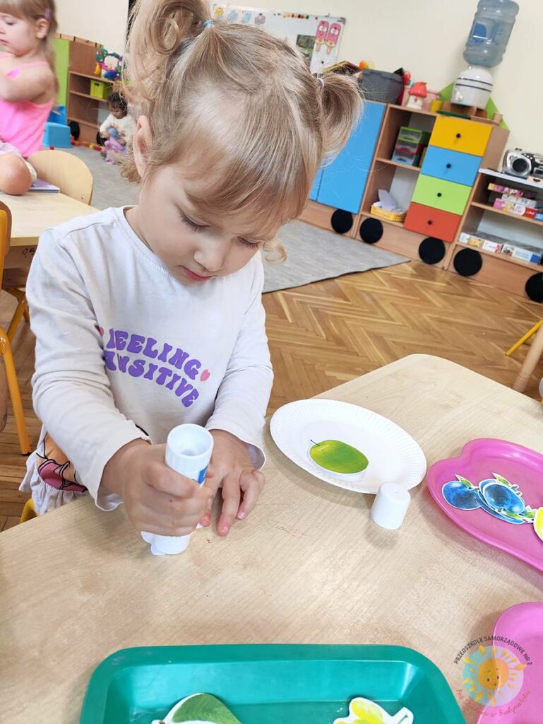 Siedzące dzieci przy stole i wykonują pracę plastyczną - Przedszkole Samorządowe Nr 2 Pod Słonkiem w Białymstoku