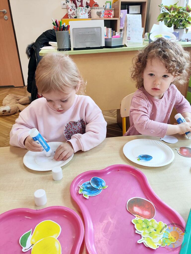 Siedzące dzieci przy stole i wykonują pracę plastyczną - Przedszkole Samorządowe Nr 2 Pod Słonkiem w Białymstoku