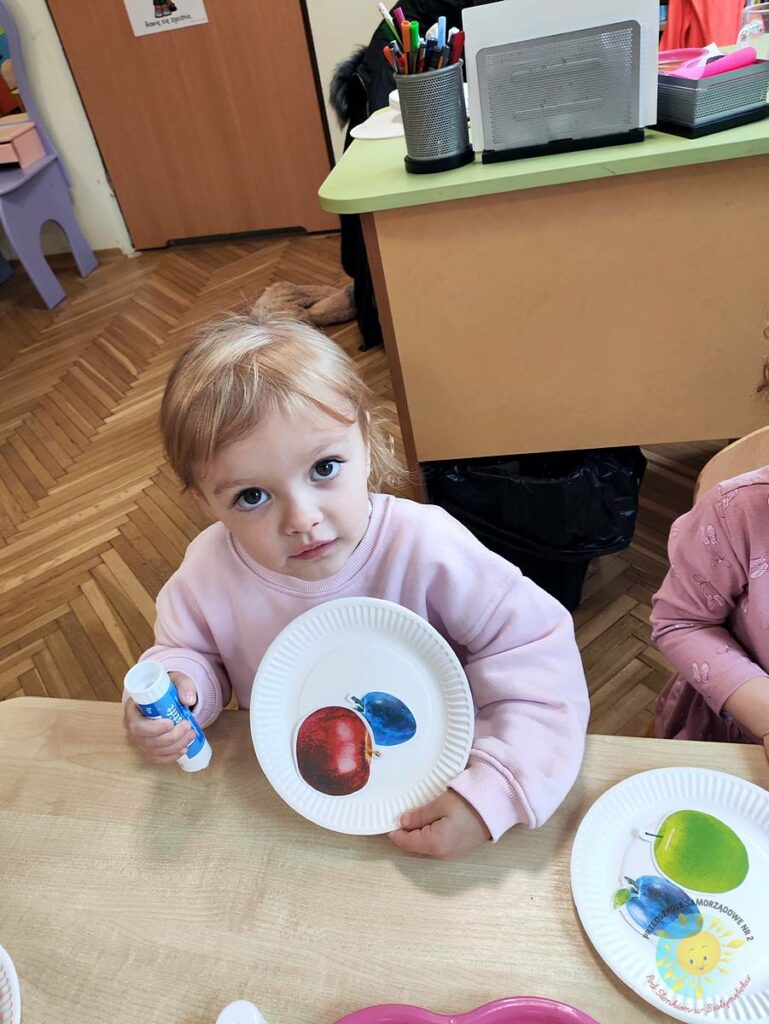 Siedzące dzieci przy stole i wykonują pracę plastyczną - Przedszkole Samorządowe Nr 2 Pod Słonkiem w Białymstoku