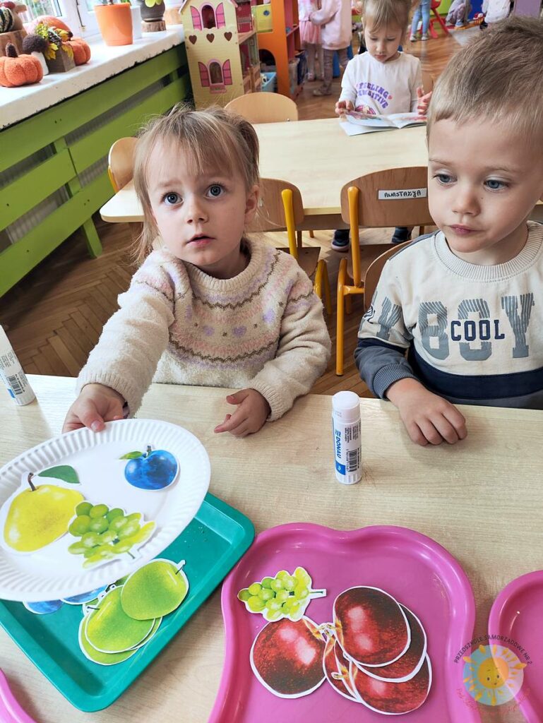 Siedzące dzieci przy stole i wykonują pracę plastyczną - Przedszkole Samorządowe Nr 2 Pod Słonkiem w Białymstoku