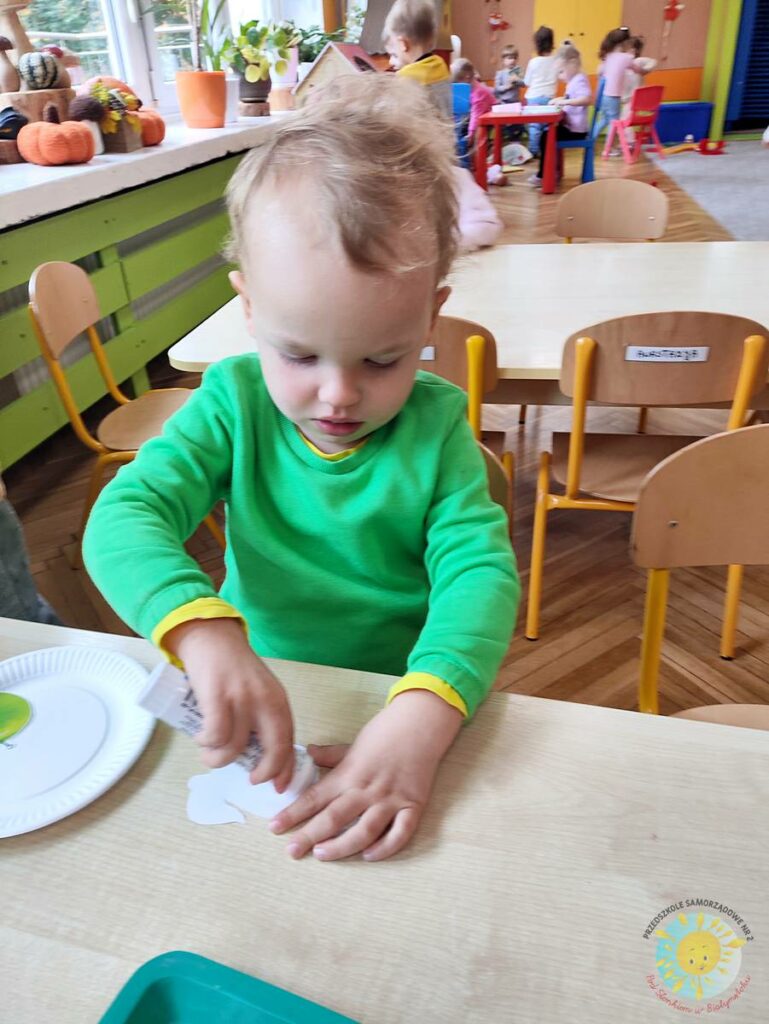 Siedzące dzieci przy stole i wykonują pracę plastyczną - Przedszkole Samorządowe Nr 2 Pod Słonkiem w Białymstoku
