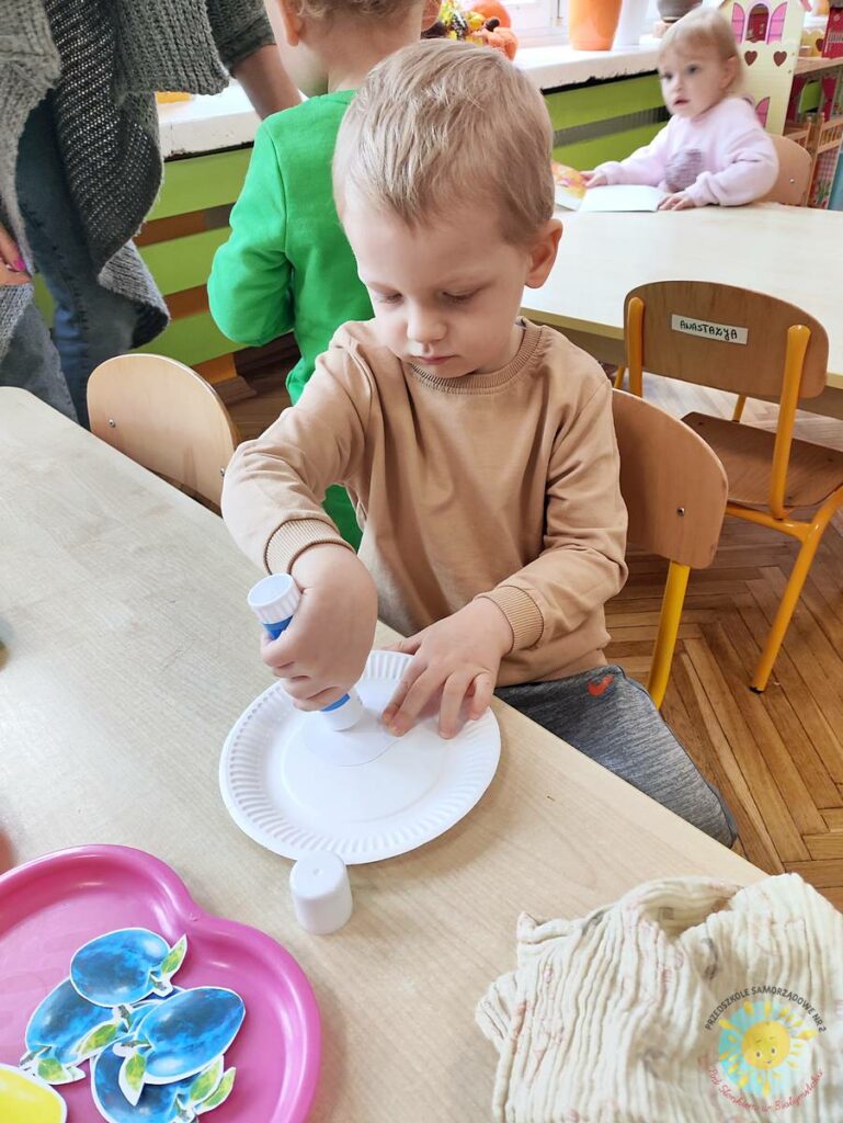 Siedzące dzieci przy stole i wykonują pracę plastyczną - Przedszkole Samorządowe Nr 2 Pod Słonkiem w Białymstoku