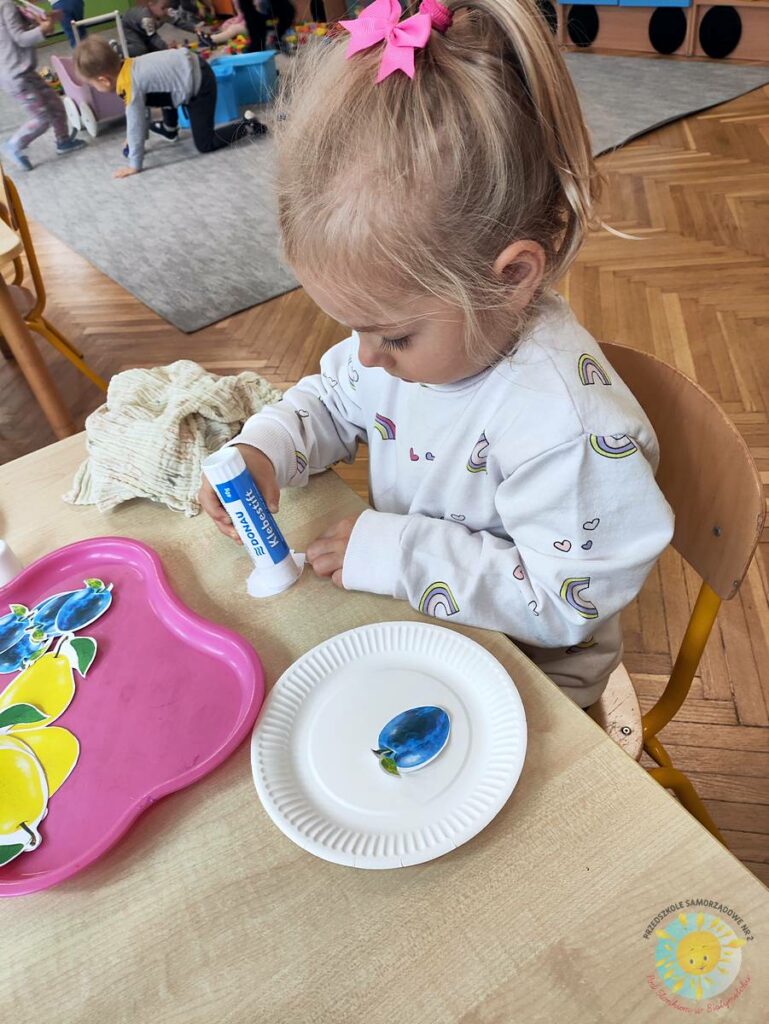 Siedzące dzieci przy stole i wykonują pracę plastyczną - Przedszkole Samorządowe Nr 2 Pod Słonkiem w Białymstoku