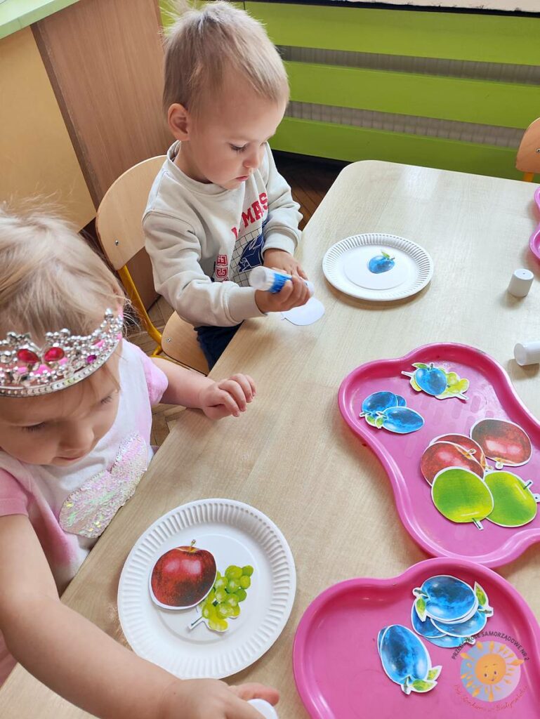 Siedzące dzieci przy stole i wykonują pracę plastyczną - Przedszkole Samorządowe Nr 2 Pod Słonkiem w Białymstoku