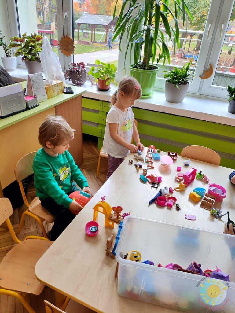 Siedzące dzieci przy stole i wykonują pracę plastyczną - Przedszkole Samorządowe Nr 2 Pod Słonkiem w Białymstoku